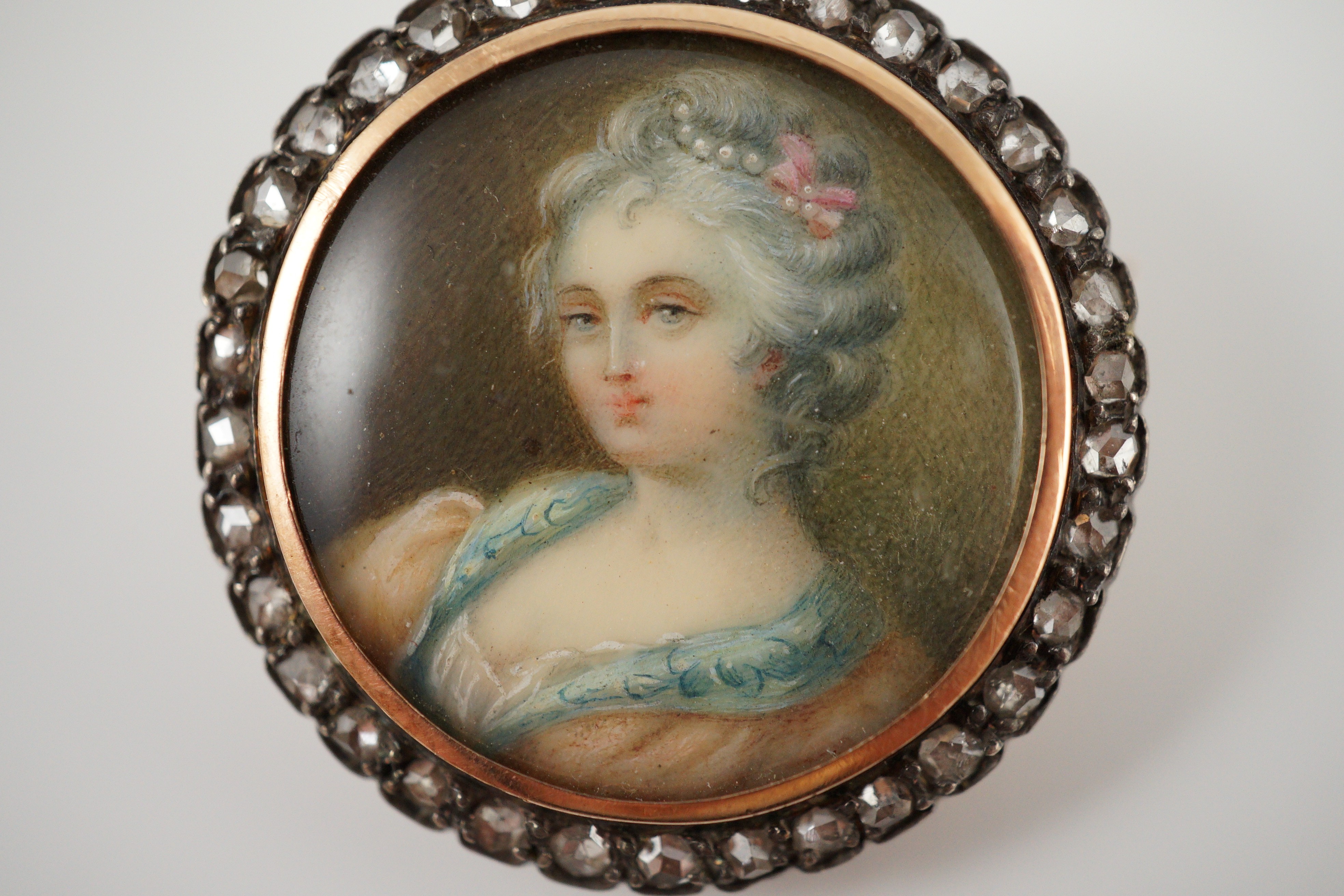 An Edwardian diamond set circular gold brooch with inset miniature portrait bust of a lady